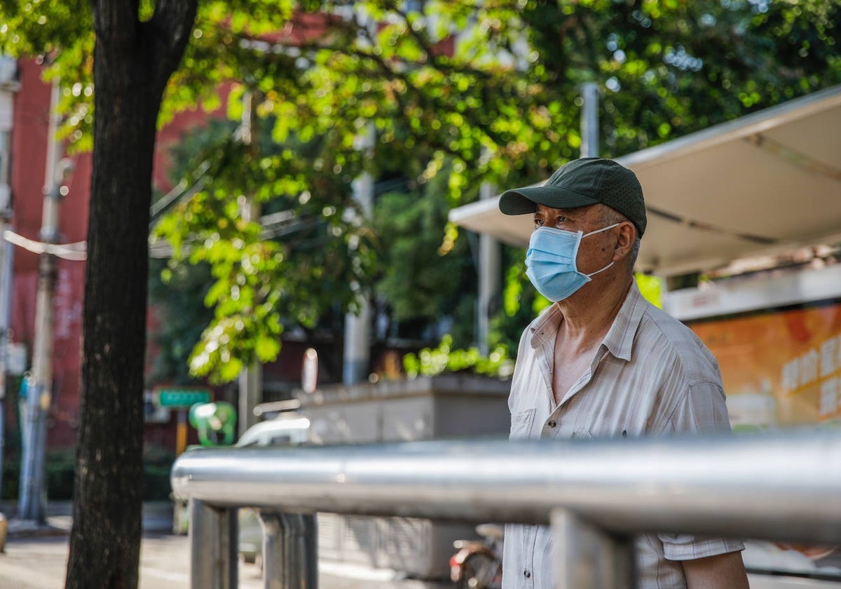 Un hombre con mascarilla espera el autobús en Beijing (China)