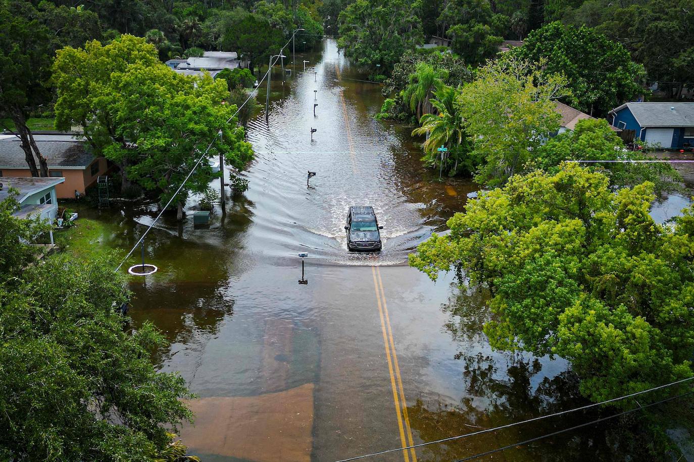 Una vista aérea muestra un vehículo circulando por una calle inundada en New Port Richey, Florida