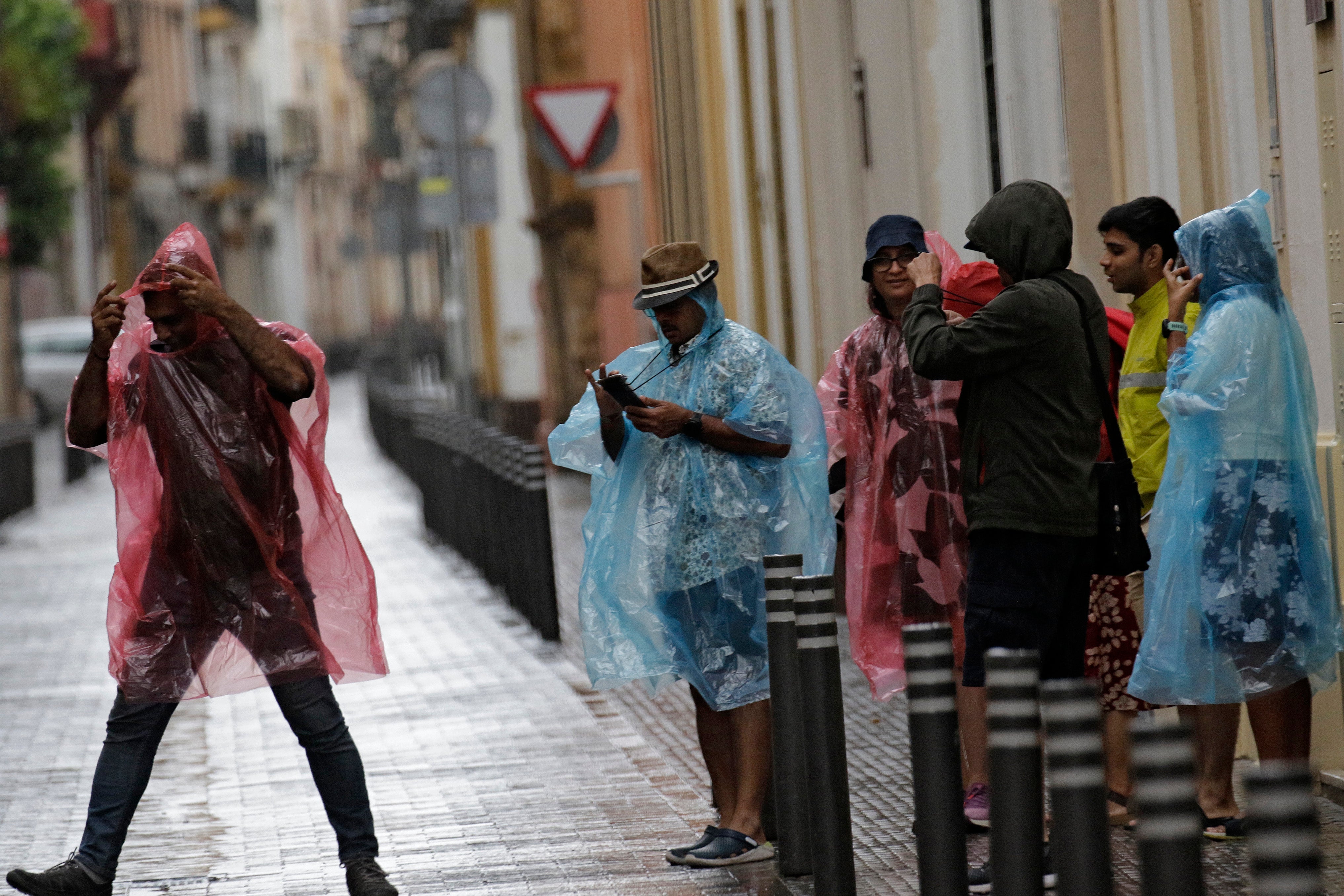 Varias personas intentado resguardarse de la lluvia en Sevilla. 