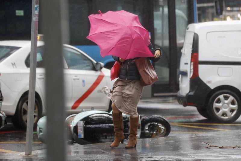 Una viandante se enfrenta a las fuertes rachas de viento mientras camina por una calle del centro de Madrid