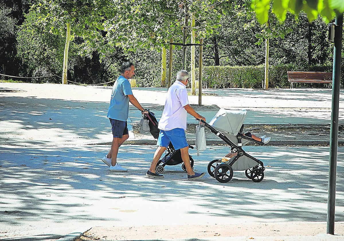 Dos padres pasean con bebés en el parque del Retiro, Madrid