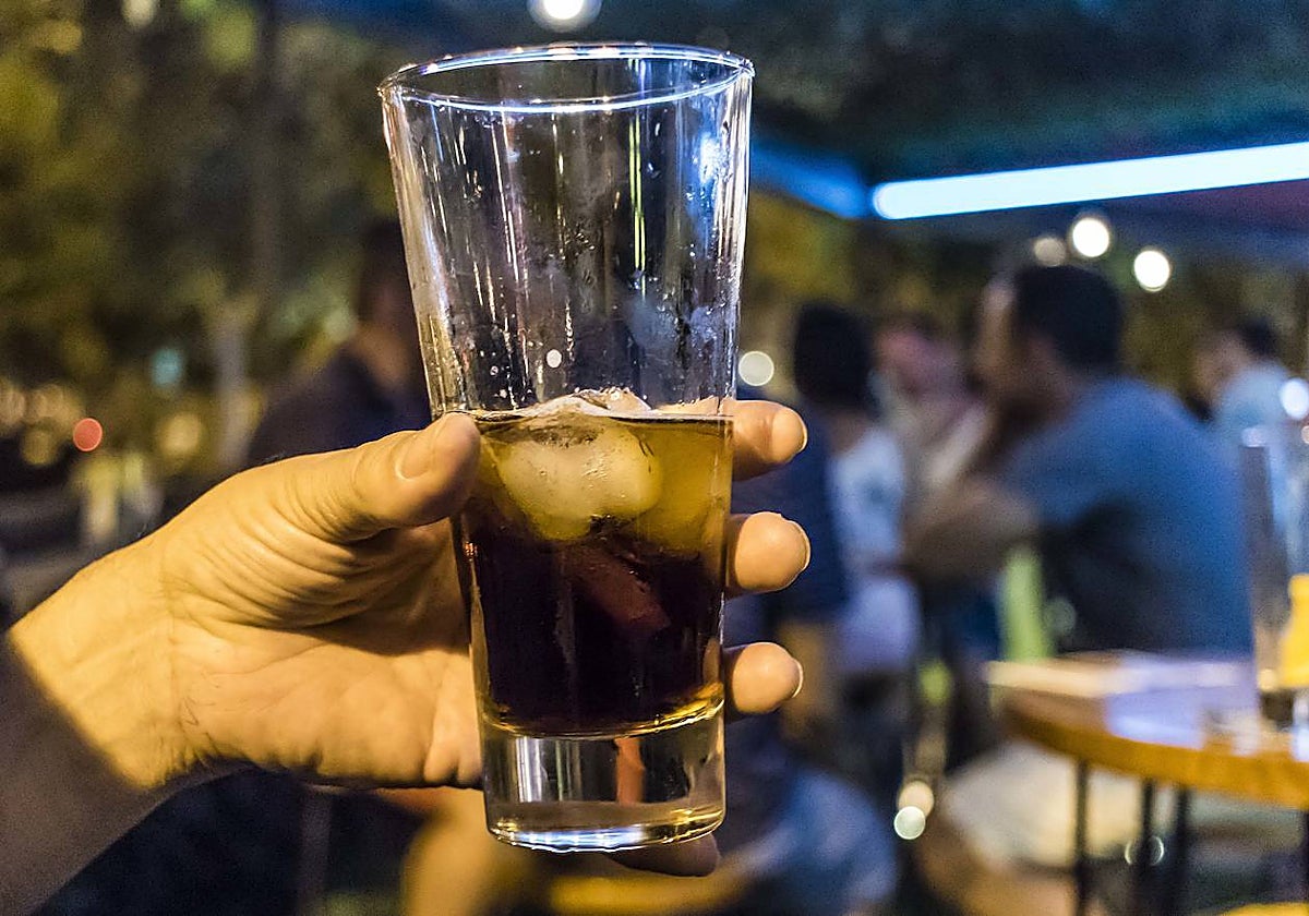 Una persona sostiene un vaso con una bebida alcohólica