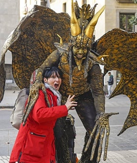 Imagen secundaria 2 - Lorena, arriba, se viste todos los días de monstruo en la Plaza Mayor. La mayor parte de estos personajes son peruanos, país de donde proceden muchos de los trajes. Abajo a la derecha una de las estatuas vivientes de Barcelona, donde no ha llegado el fenómeno de los muñecos 