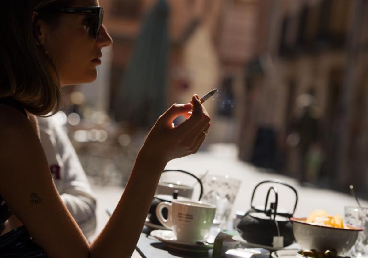 Una mujer fuma en una terraza de bar