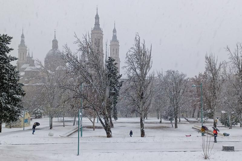 Varias personas caminan durante la nevada caída el viernes en Zaragoza, cerca de la Basílica del Pilar