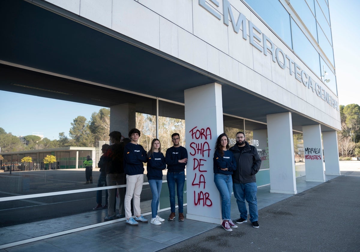 Miembros de S'ha Acabat! junto a una pintada contra la entidad en el campus de la UAB