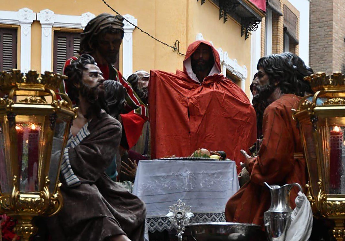 La imagen de Cristo de la Hermandad de la Sagrada Cena ha tenido que ser protegida con un capote ante el chaparrón de lluvia y barro que ha caído en Sevilla