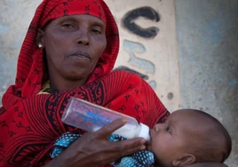 Una mujer africana da un biberón a un bebé