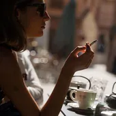 Una mujer fuma un cigarrillo en la terraza de un bar