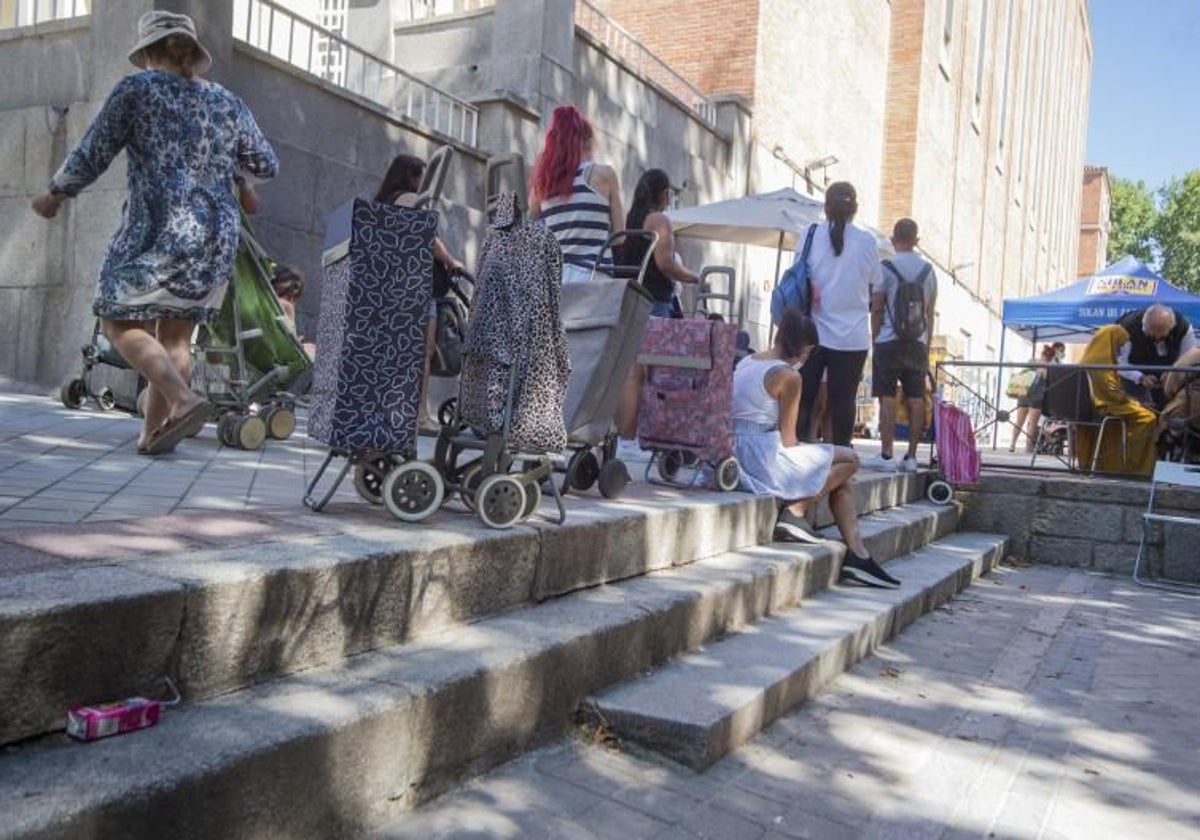 Un grupo de personas espera antela puerta de una Iglesia para recoger una bolsa de alimentos