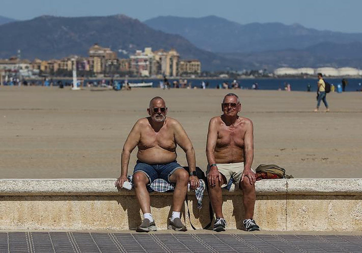 Dos hombres toman el sol en la playa de La Malvarrosa, en 2023