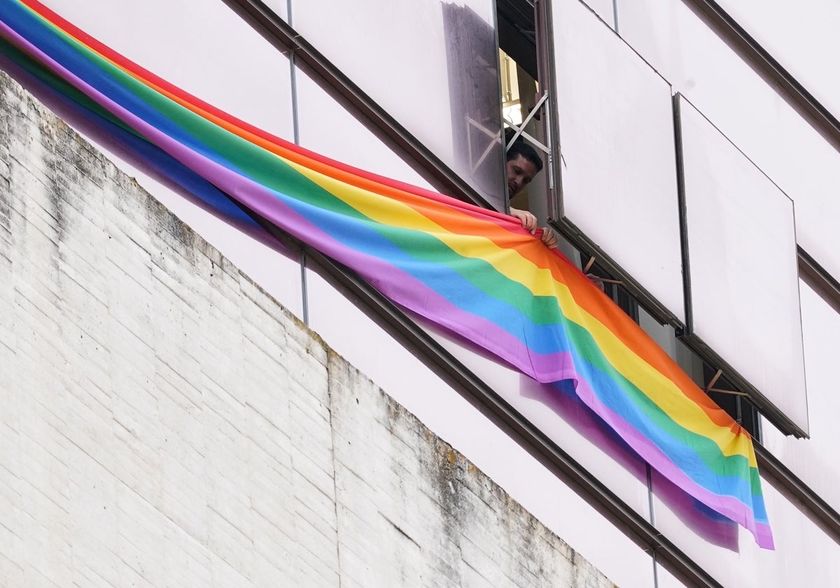 Un operario cuelga una bandera LGTB en un edificio institucional