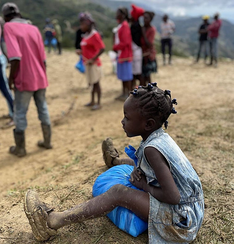 Una niña haitiana recoge una bolsa de ayuda facilitada por la Fundación Proclade