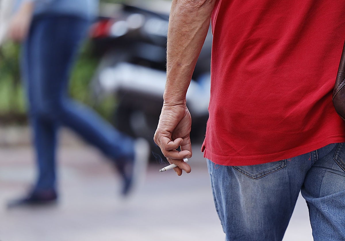 Un hombre fumando por la calle