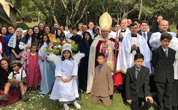 Imagen principal - En su página web, el obispo que ahora se encarga de la dirección espiritual de las exmonjas de Belorado muestra varias de sus acciones, como el primer congreso sedevacantista de Brasil (arriba) en el que sorprende el alto número de niños entre los participantes. También aparece un retiro espiritual de jóvenes, cinco en este caso, ataviadas con mantilla y vestimenta tradicional, e incluso una imagen de la consagración episcopal , en lo que parece una improvisada capilla con una mesa de despacho como altar y la percha del alba al fondo.