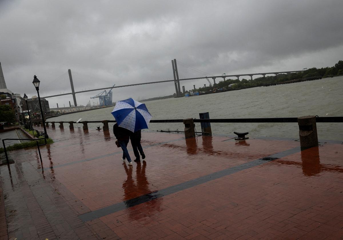 Una pareja camina bajo la lluvia por River Street mientras la tormenta tropical Debby avanza hacia Georgia.