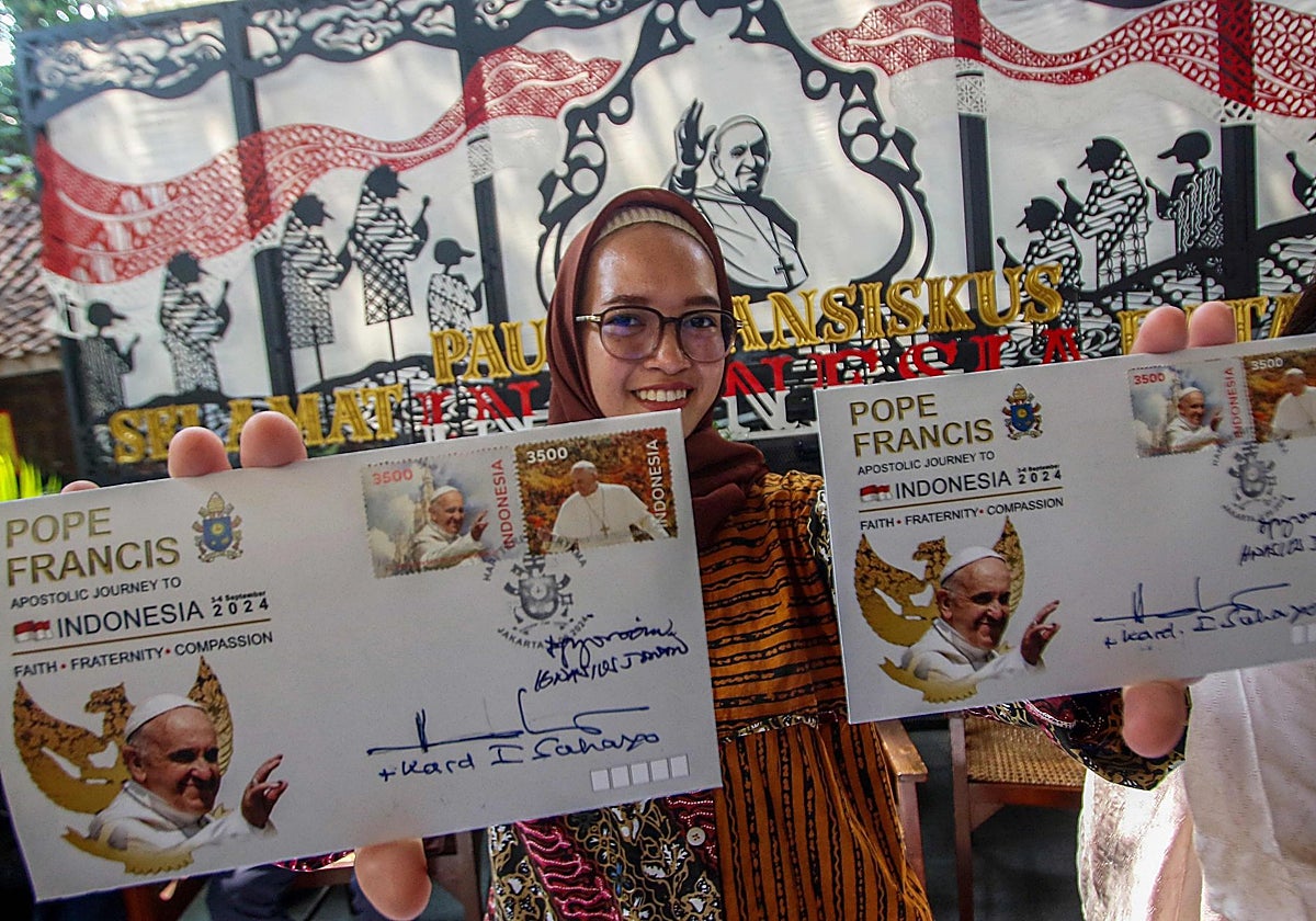 Una mujer muestra muestras de una nueva serie de sellos antes de la visita del Papa Francisco