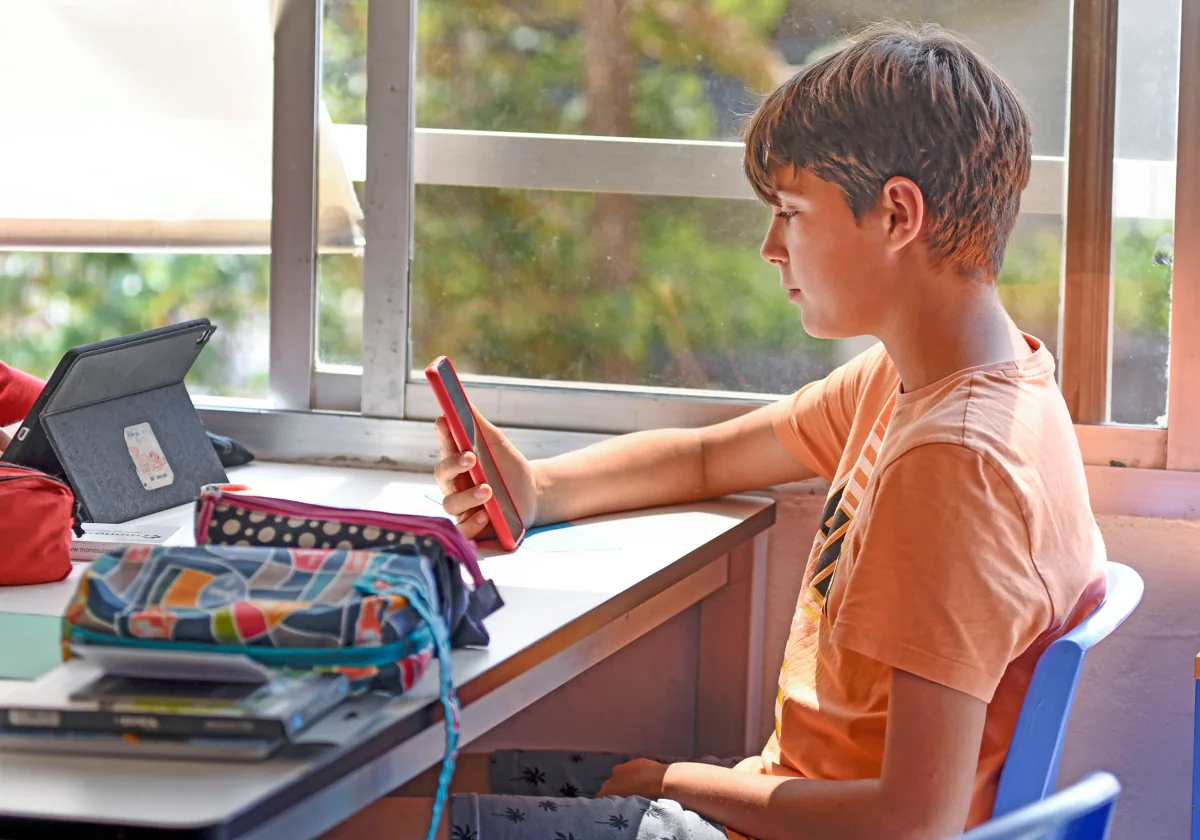 Imagen de archivo de un alumno usando su teléfono móvil en el aula