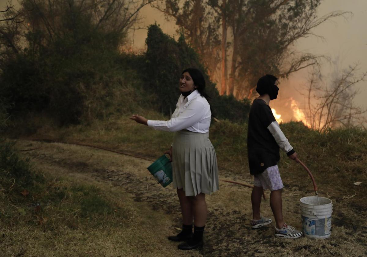 Personas intentan apagar un incendio con baldes de agua este martes