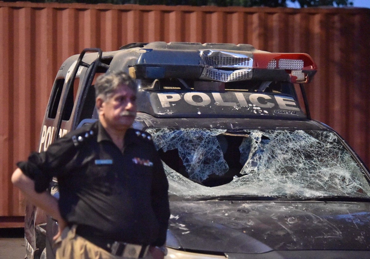 Un policía pakistaní monta guardia junto a un vehículo policial dañado