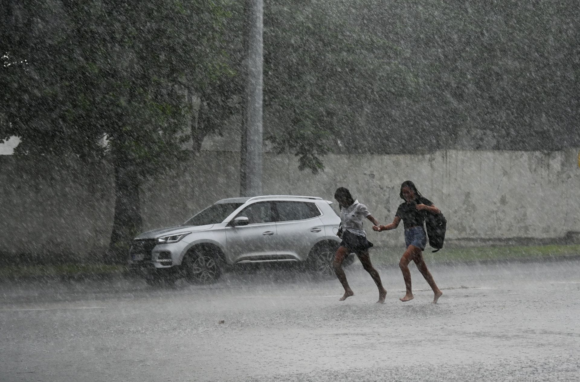 Dos personas corren bajo las primeras lluvias propiciadas por Milton