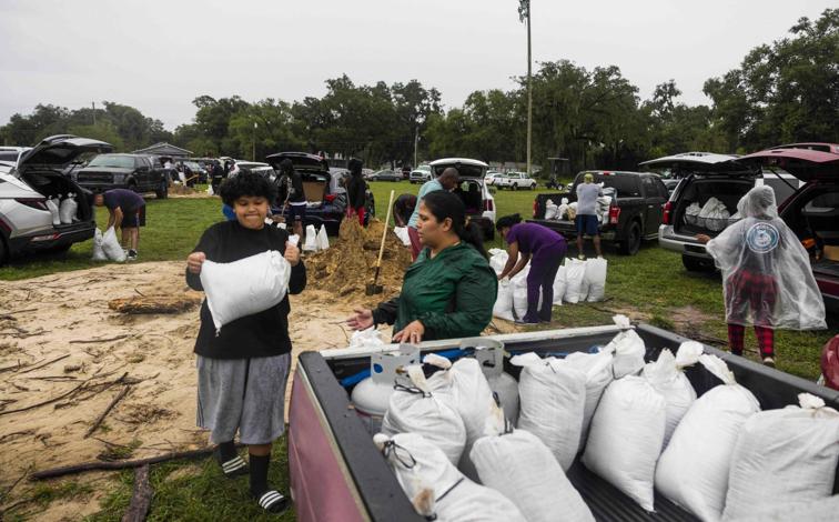 Imagen principal - Residentes de Orlando (Florida) hacen acopio de sacos terreros (arriba). En Fort Myers se dejan notar los efectos de un tornado y un hombre protege un inmueble con planchas de madera