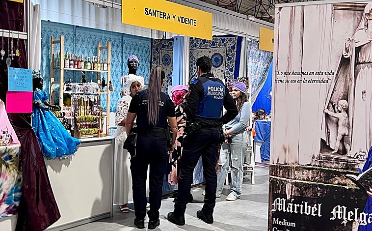 Imagen principal - En la foto superior, la Policía Local inspecciona los productos a la venta en una de las casetas que se promociona como «santera y vidente». En la inferior, productos a la venta en otro de los puestos de la feria esotérica. En la última foto, una pareja de la Policía Local dialoga con la organización de evento, después del incidente