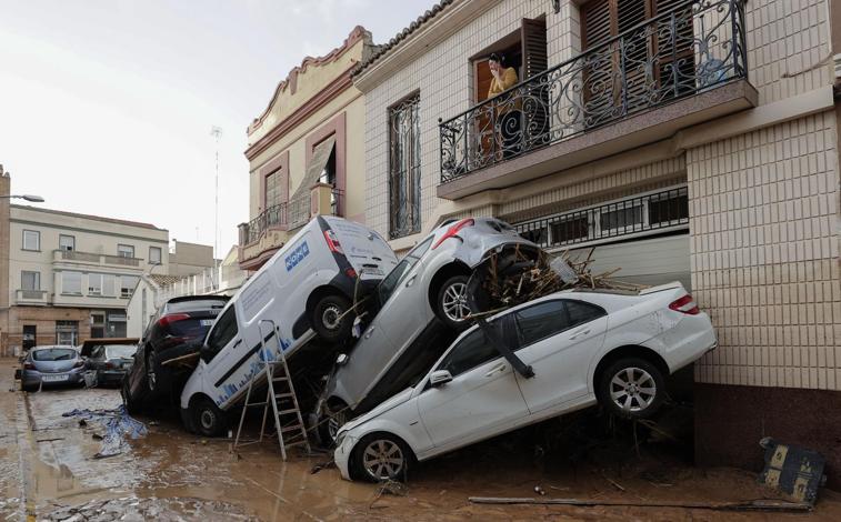 Imagen principal - Barro, vehículos amontonados y escombros cubren las calles de Paiporta tras la riada