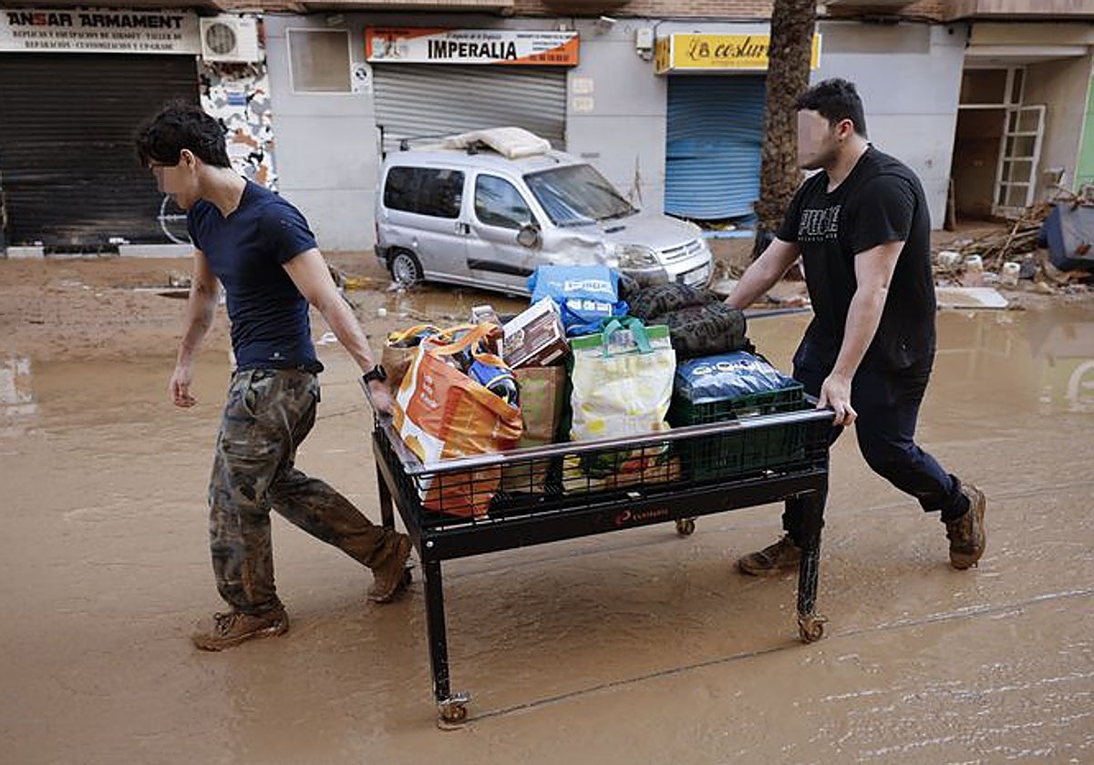 Dos hombres trasladan enseres, en una mesa convertida en carro, en la localidad de Paiporta