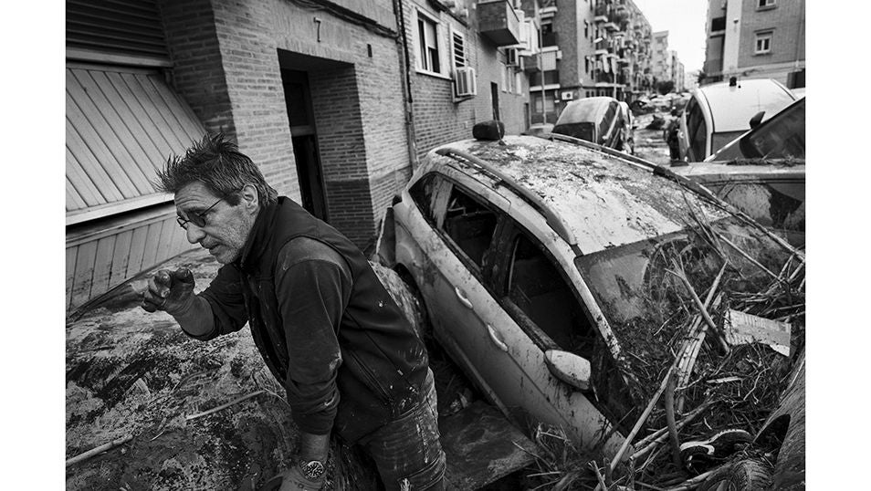 Un hombre mira entre los escombros que bloquean la entrada a su domicilio en la localidad de Paiporta