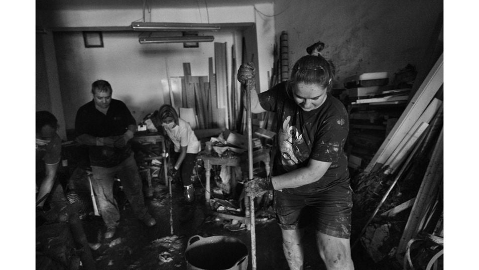 Una voluntaria ayuda a sacar agua y lodo de un local del municipio de Las Torres
