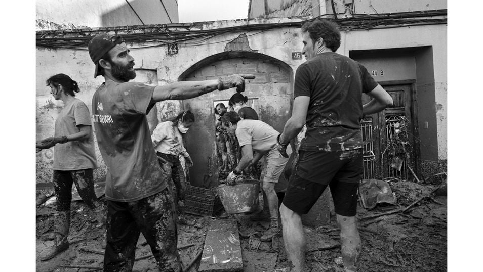 Un grupo de voluntarios, en labores de desescombro y limpieza de lodo y barro en Paiporta, localidad reducida a escombros tras el paso de la DANA