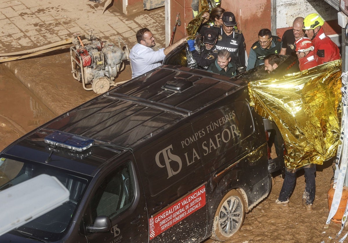 Un furgón de la funeraria sale de un garaje con cadáveres localizados tras el paso de la DANA, en el barrio de la Torre, Valencia