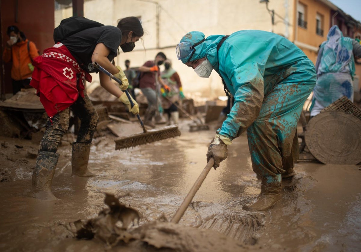 Voluntarios retiran barro de las calles con palas y cepillos, en el barrio de El Raval, Algemesí