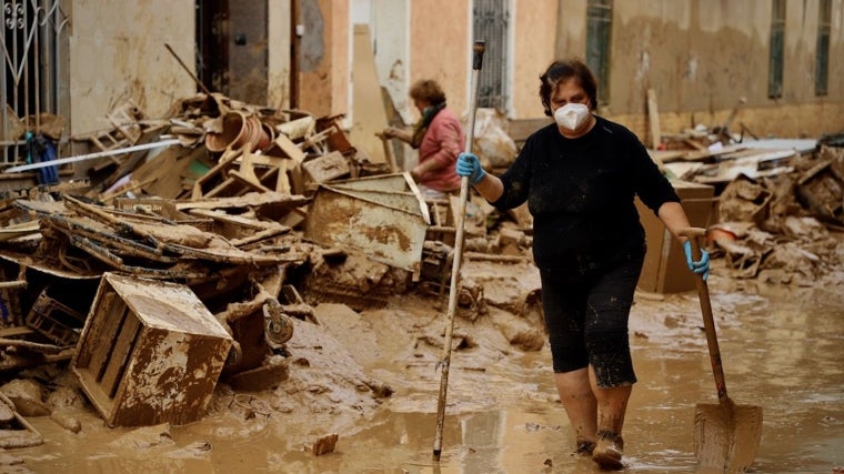 Los vecinos de Masanasa retiraban el barro tras la riada, que llegó a dos metros de altura en sus casas