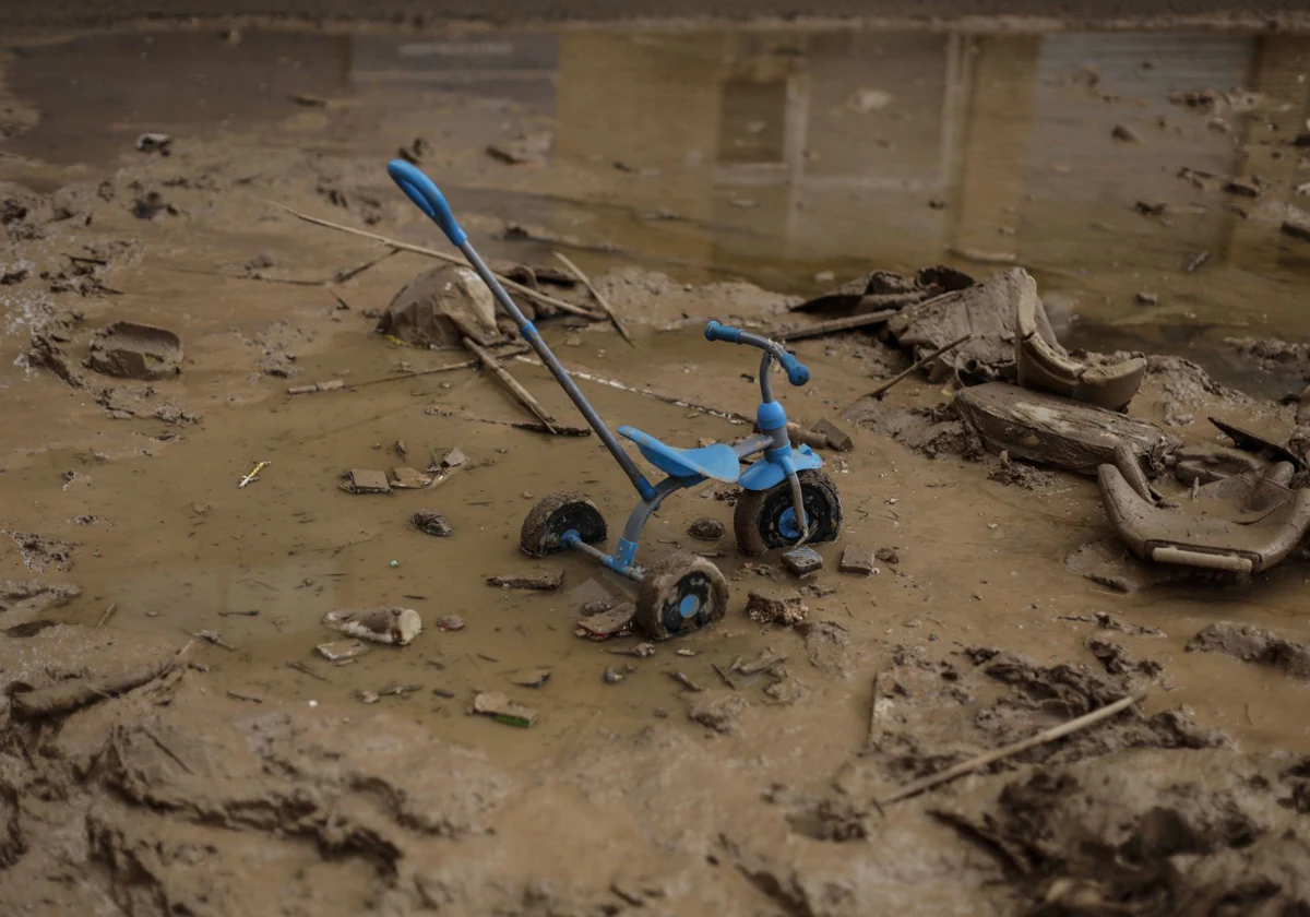 El triciclo de un niño sobre en barro de una calle de Paiporta, Valencia