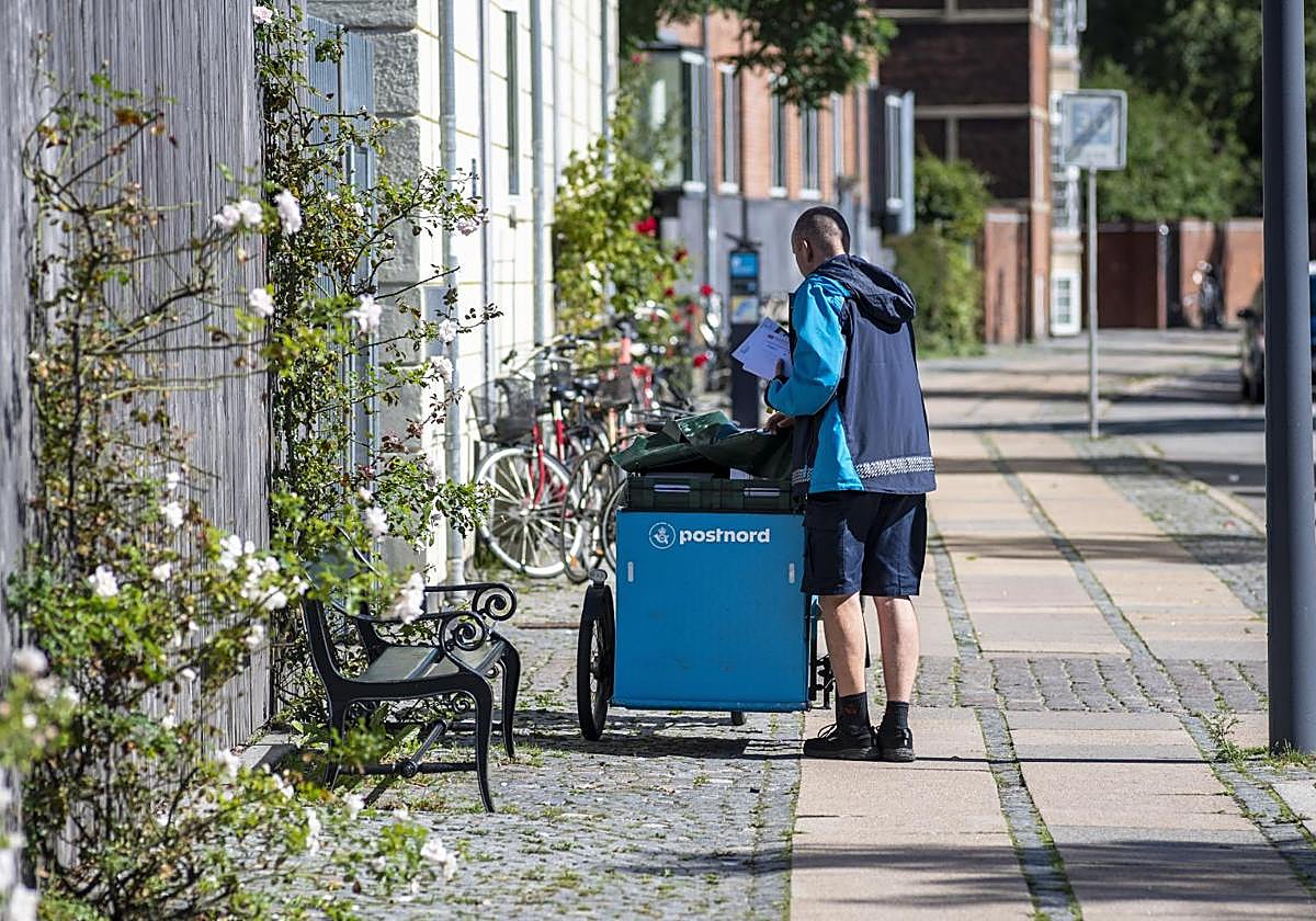 Un empleado de PostNord entrega cartas en Noerrebro, Copenhague, Dinamarca