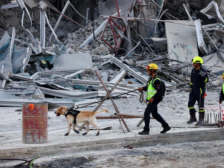 Un agente de policía pasea con un perro cerca de un edificio que se derrumbó tras el fuerte terremoto que sacudió el centro de Myanmar.