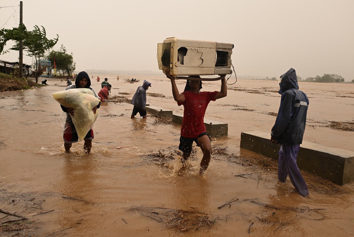 Residentes de la Ciudad de Ilagan, al norte de Filipinas, llevando sus pertenencias por el impacto de las las fuertes lluvias del tifón Torajii (conocido localmente como Nika)