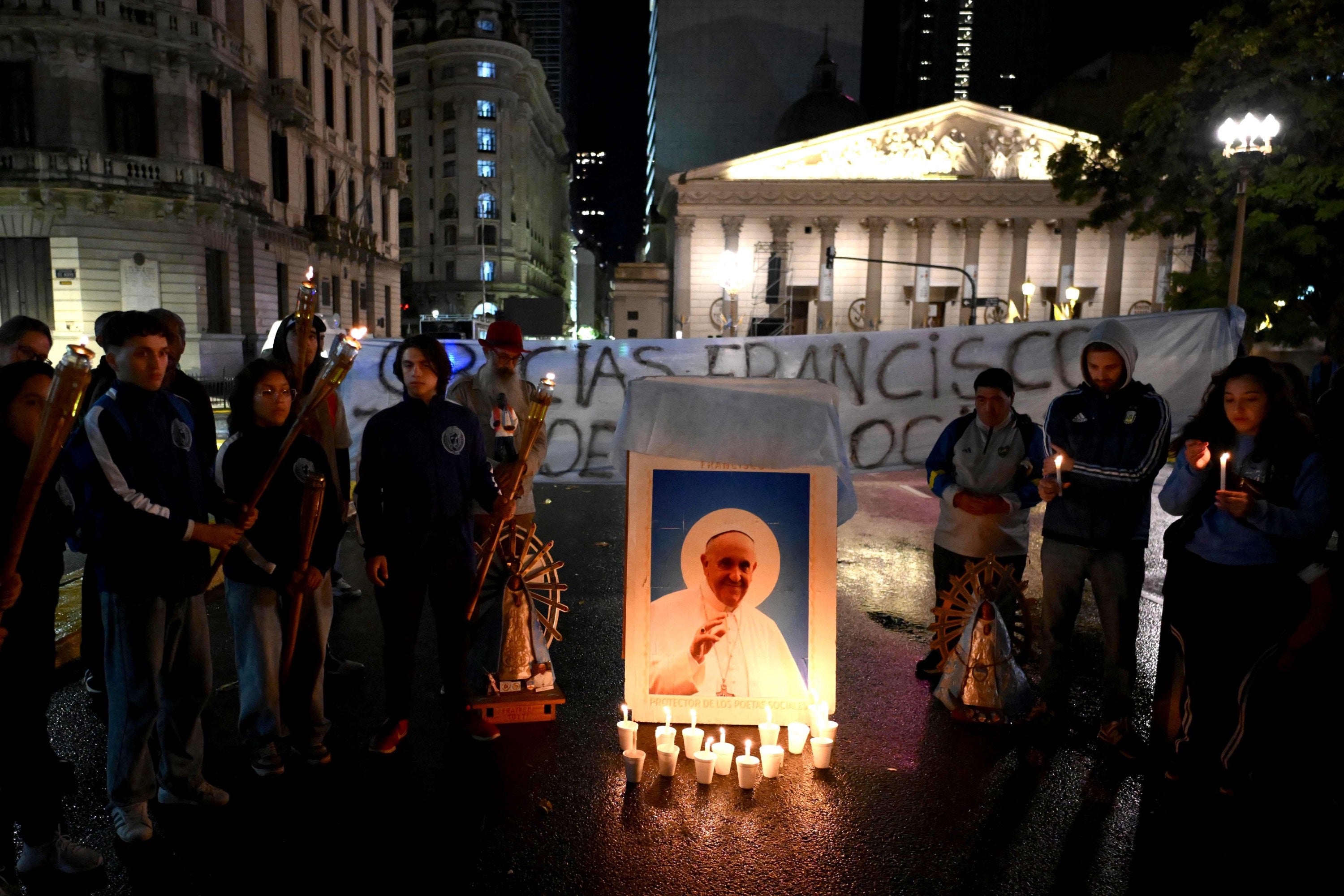 Católicos rezan en torno a una imagen de Francisco iluminada por velas frente a la catedral de Buenos Aires