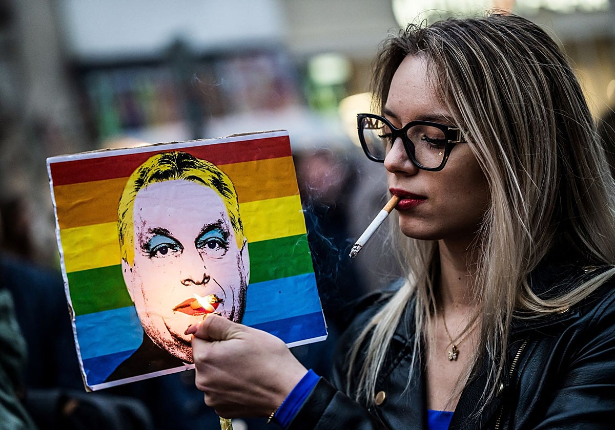 Una mujer enciende un cigarrillo colocado en un cartel que representa de manera irónica al primer ministro de Hungría, Viktor Orbán