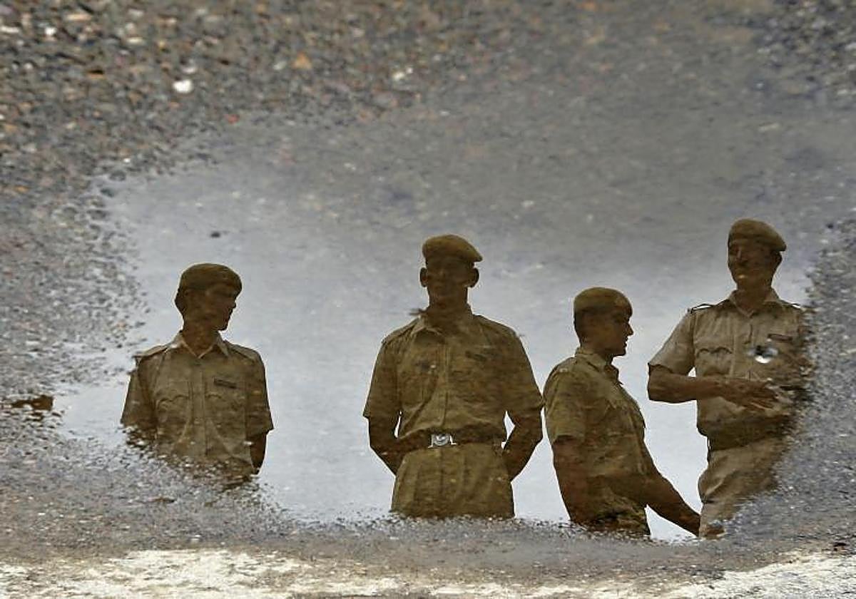 Agentes de la Policía india reflejados en un charco