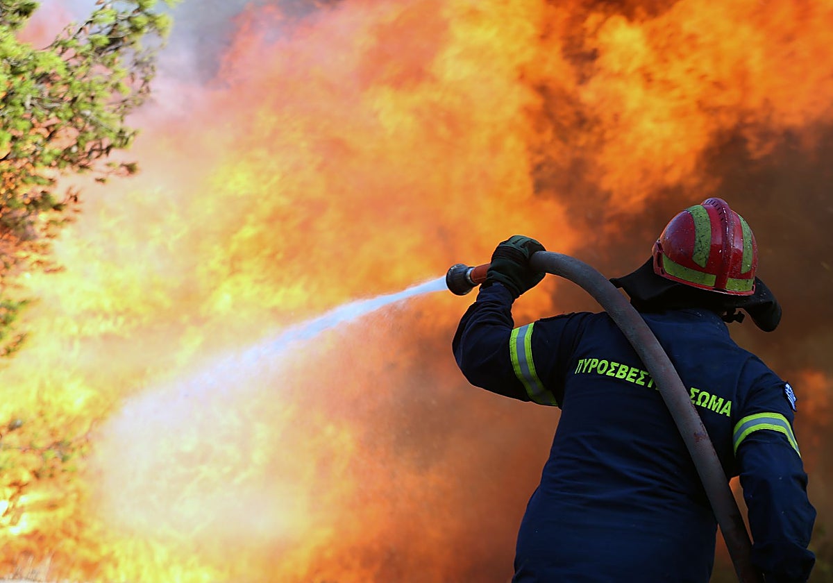 Un bombero combate un incendio forestal que se declaró en terrenos baldíos y matorrales bajos en la localidad de Harvalo, Keratea