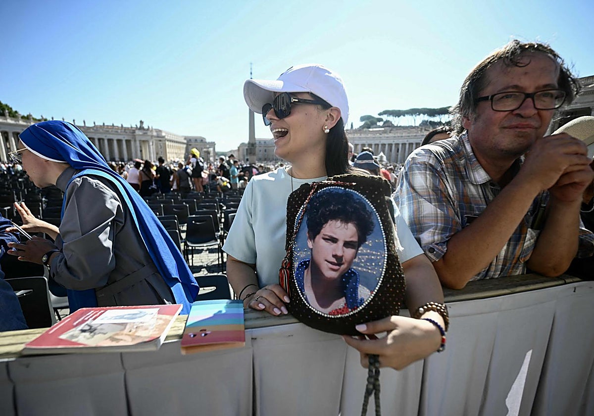Una mujer sostiene un retrato de Acutis, el primer santo milenial