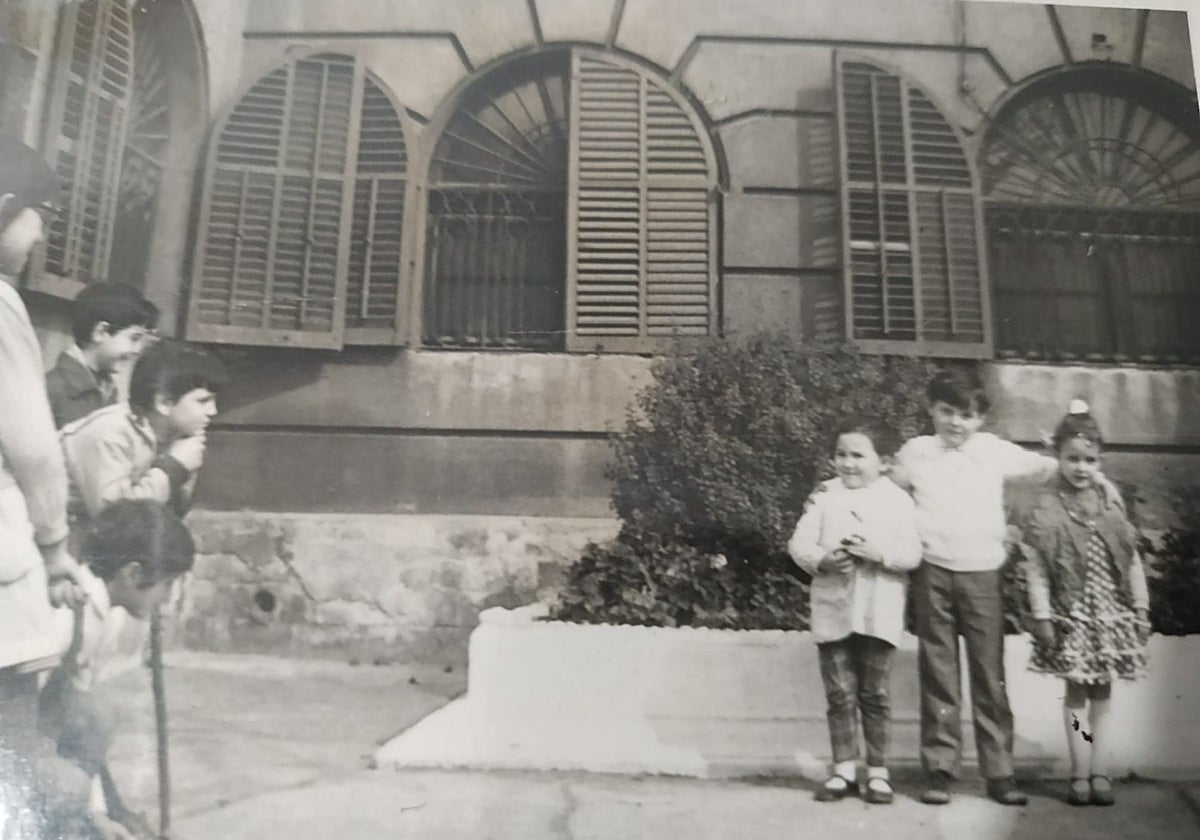 Marc, de pequeño, en el centro con dos amigas, y otro grupo de amigos jugando en el patio del cementerio, frente a la casa en la que viven