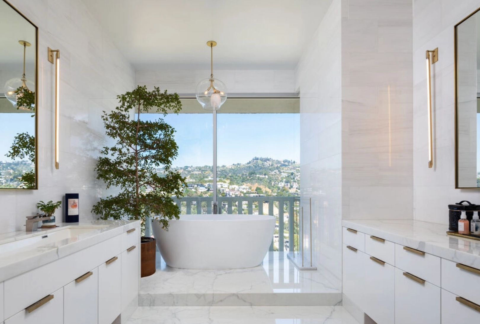 El baño del dormitorio principal cuenta con una gran bañera situada junto a un gran ventanal con vistas a las colinas de Hollywood