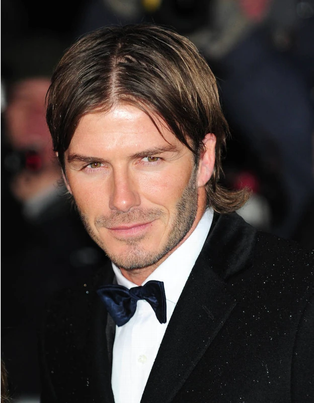 David Beckham con el pelo largo y peinado con raya en el medio.