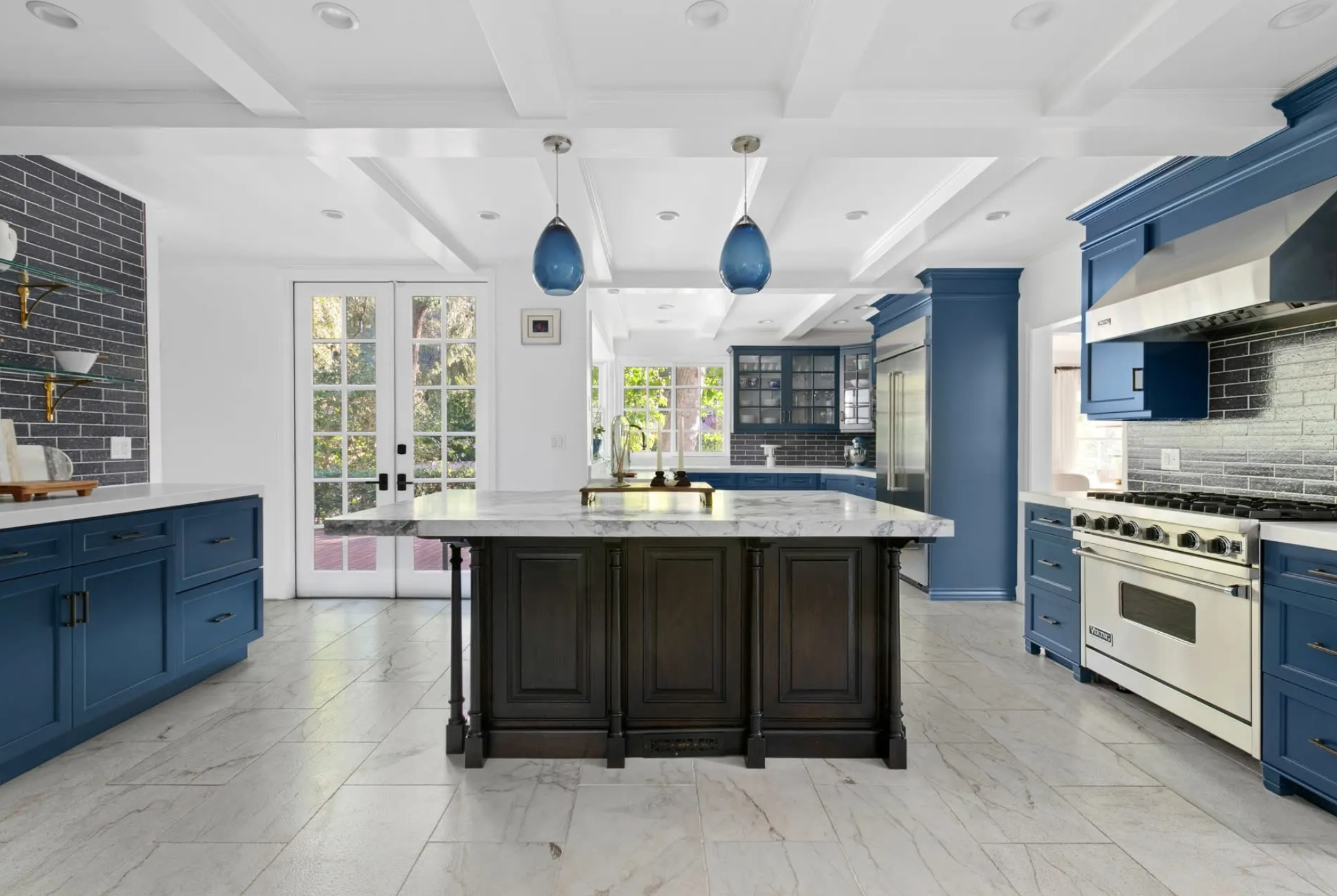 La cocina dispone de gabinetes en azul cobalto, electrodomésticos de acero inoxidable Viking y una gran isla central
