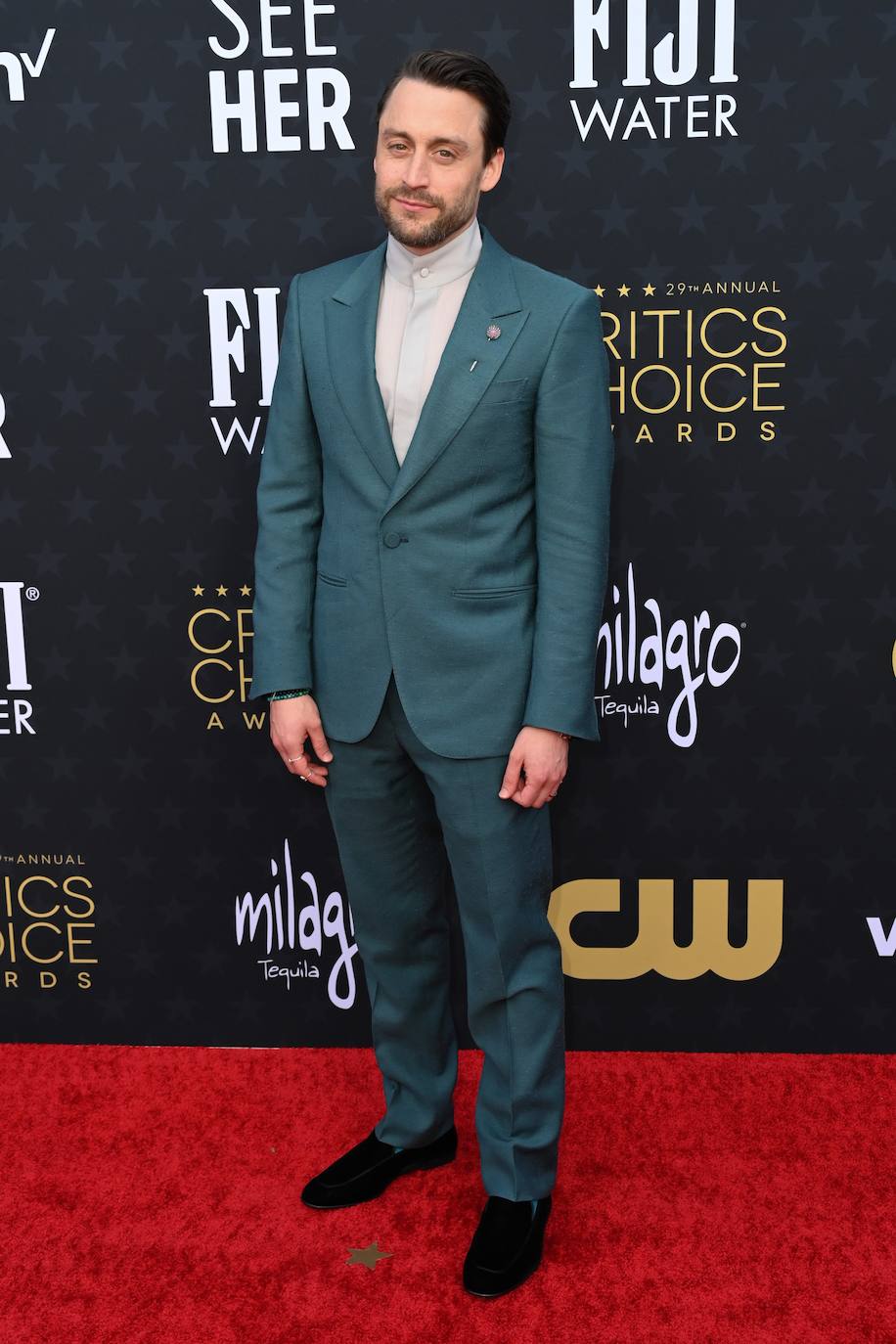 Kieran Culkin con traje verde y camisa con cuello subido. 