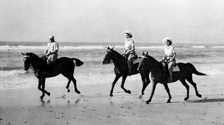 Las dos hermanas cabalgando sus respectivos caballos por la orilla del mar.